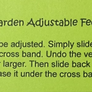 Peut inclure: Une carte d'instructions verte pour ajuster la taille d'un "Granny's Garden Adjustable Fedorable". Le texte explique comment ajuster le bandeau en le faisant glisser vers la droite jusqu'&agrave; ce que la partie velcro apparaisse, puis en d&eacute;faisant le velcro et en le refermant pour rendre le bandeau jusqu'&agrave; 1,9 cm plus petit ou plus grand.