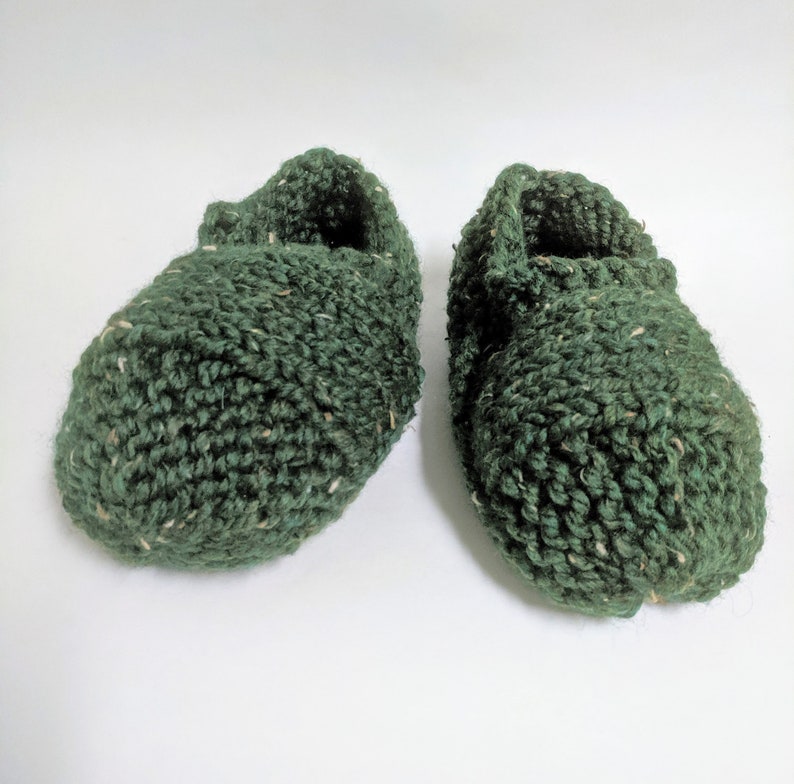 May include: A pair of green knitted slippers with a textured surface.