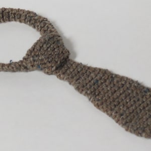 Peut inclure: Une cravate en crochet marron avec un n&oelig;ud en haut.