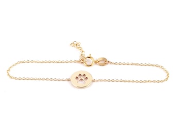 May include: A gold chain bracelet with a circular charm featuring a paw print cutout.
