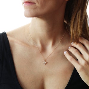 May include: A gold chain necklace with a small hummingbird pendant. The hummingbird is made of gold and has a clear crystal body.