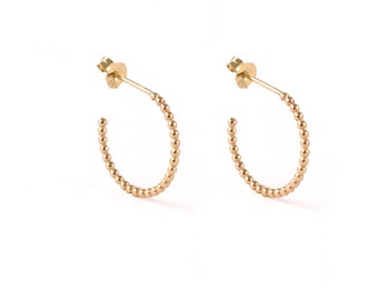 May include: A pair of gold hoop earrings with a beaded design. The earrings are small and delicate.