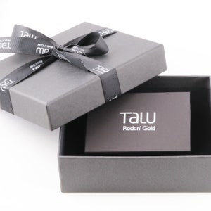 May include: A gray gift box with a black ribbon and bow. The box is open and the inside is lined with black velvet. A small gray card with the text "TALU Rock 'n' Gold" is inside the box.