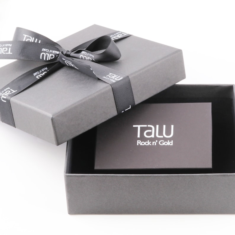 May include: A gray gift box with a black ribbon and bow. The box is open and the inside is lined with black velvet. A small gray card with the text "TALU Rock 'n' Gold" is inside the box.