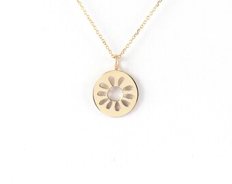 May include: A gold necklace with a delicate, circular pendant featuring a cutout design resembling a flower.