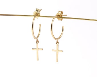 May include: Gold hoop earrings with a dangling cross charm. The earrings are simple and elegant.