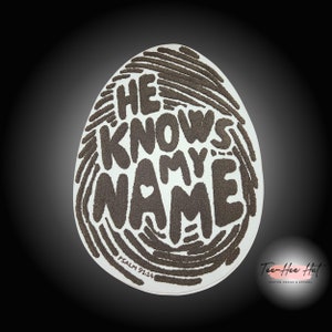 May include: A white sticker with a brown fingerprint design. The words "HE KNOWS MY NAME" are written in a stylized font inside the fingerprint. The words "PSALM 91:14" are written below the fingerprint.