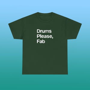 May include: A dark forest green short-sleeve t-shirt featuring the white text "Drums Please, Fab" printed in a clean, sans-serif font on the center of the chest. The garment has a classic crew neckline and a standard, straight-cut silhouette.