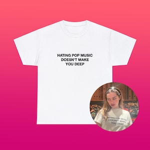 May include: White t-shirt with the text "HATING POP MUSIC DOESN'T MAKE YOU DEEP" in black, centered on the front. A circular image of a person wearing the same shirt is in the lower right corner. The background is a gradient of pink and red.