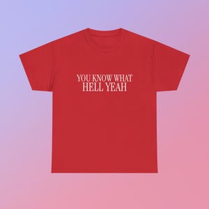 以下が含まれることがあります： 胸に白い文字で「YOU KNOW WHAT HELL YEAH」と書かれた赤いTシャツ。 シャツは無地の赤色で、半袖とクルーネックです。