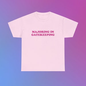 May include: A pink t-shirt with the text "MAJORING IN GATEKEEPING" printed in pink.