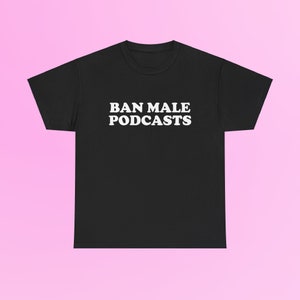 Könnte beinhalten: Schwarzes T-Shirt mit dem weißen Text "BAN MALE PODCASTS" in einer fetten, serifenlosen Schrift. Das Shirt wird vor einem rosa Hintergrund präsentiert. Ein lässiges Kleidungsstück.