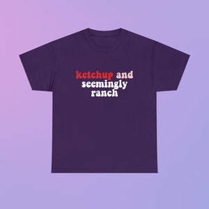 May include: Purple t-shirt with the text "ketchup and seemingly ranch" in red and pink letters.