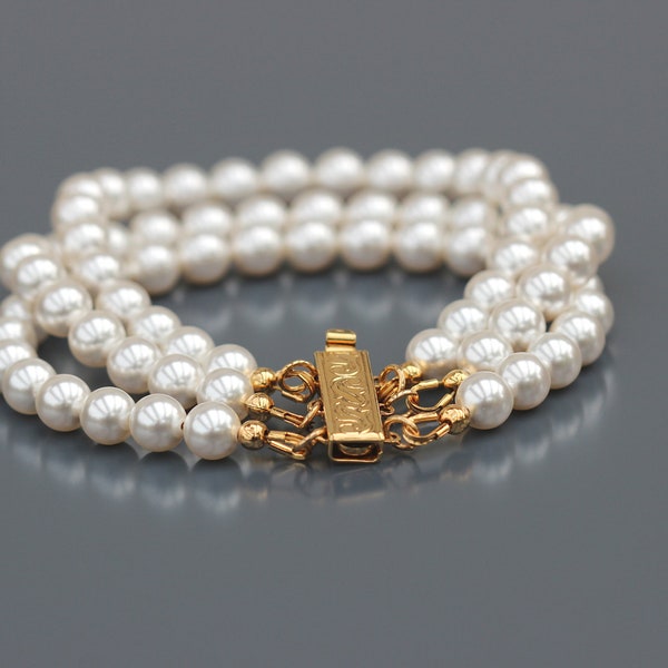 Bracelet trois rangs de Perles rondes nacrées blanches en Cristal. Fermoir finition or.