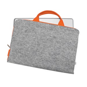 Könnte beinhalten: Eine graue Filz-Laptoptasche mit orangefarbenen Griffen und einem Reißverschluss. Die Tasche ist so konzipiert, dass sie einen Laptop vor Kratzern und Stößen schützt.