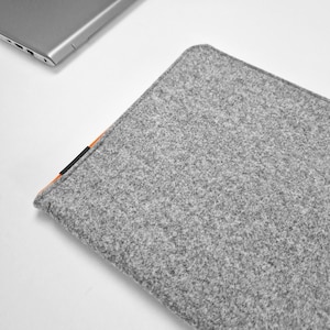 Front photo of light grey felt case with laptop inside. Orange zipper opens on the side and top of the case. Durable felt, case made to fit your laptop's size.