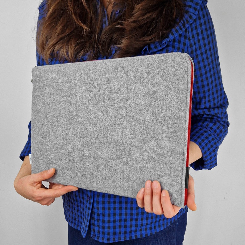 Woman holding light grey felt laptop sleeve with red zipper