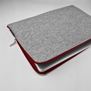 Laptop inside felt case, maroon zipper opend.