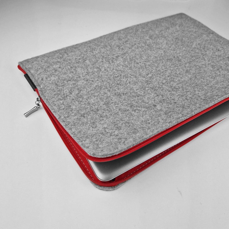 Light grey felt laptop case opend. Red zipper with silver zipper ending.