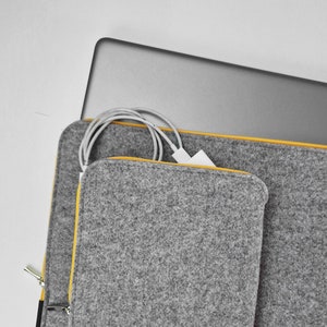 Front pocket for wires, mouse, etc. Laptop felt case with yellow zipper. Pocket firmly attached to the main part of the sleeve. Pocket takes charger wires, mouse etc.