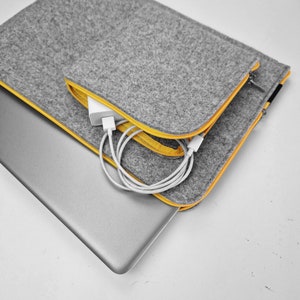 Light grey felt case with yellow zipper. 15 inch laptop cover with front pocket sewn on the main part of the sleeve. Pocket for wires, mouse, etc.