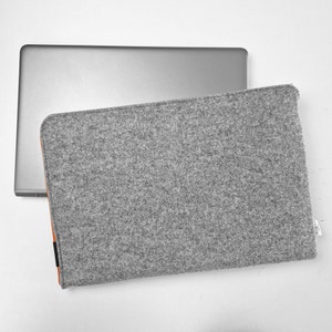 Front photo of light grey felt case with laptop inside. Orange zipper opens on the side and top of the case. Durable felt, case made to fit your laptop's size.