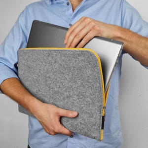 Men holding light grey felt laptop sleeve with yellow zipper. Cover opens on the side and top. Hand made felt case will fit your laptop easly. All sizes avaliable - 13 inch, 15 inch and other.