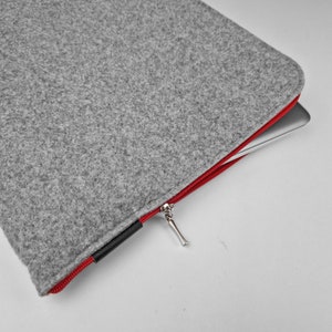 Light grey felt laptop case opend. Red zipper with silver zipper ending.