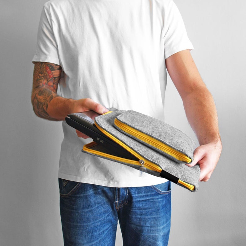 Men holding 15 inch laptop inside light grey flet sleeve. Yellow zipper opens on the side and top of the cover. Hand made laptopcase. All sizes avaliable.