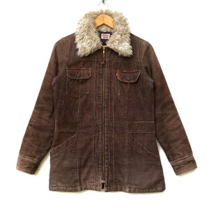 May include: A brown corduroy jacket with a faux fur collar. The jacket has a zipper closure and two flap pockets on the front.