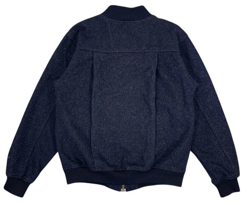 Puede incluir: Chaqueta bomber azul marino oscuro con tejido texturizado. La chaqueta tiene cuello, pu&ntilde;os y dobladillo de canal&eacute;, y cierre de cremallera frontal. La parte trasera de la chaqueta tiene un detalle de costura vertical.