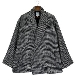 May include: A black and white patterned coat with a notched collar and two front pockets. The coat is hanging on a wooden hanger. The label reads "Jean Paul Gaultier".