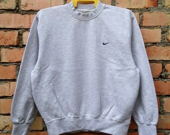 May include: A gray sweatshirt with a black Nike logo on the left chest.