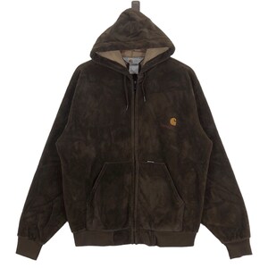 Puede incluir: Una chaqueta marrón con capucha Carhartt con cremallera y forro de polar marrón. La chaqueta tiene un gran logotipo de Carhartt en el pecho derecho.