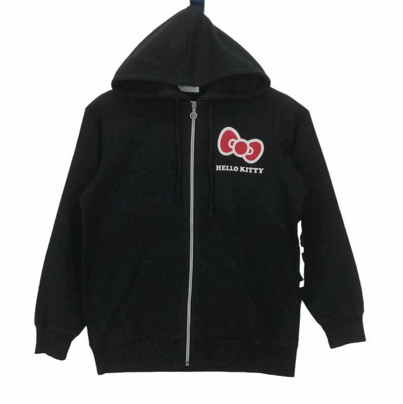 May include: Black zip-up hoodie with a red Hello Kitty bow and the text "HELLO KITTY" in white.