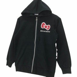 May include: Black zip-up hoodie with a red Hello Kitty bow and the text "HELLO KITTY" on the front.