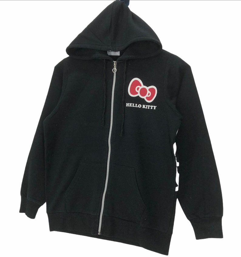 May include: Black zip-up hoodie with a red Hello Kitty bow and the text "HELLO KITTY" on the front.