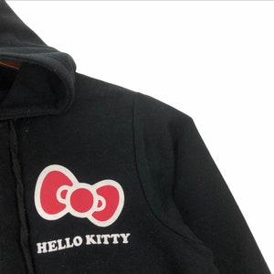 May include: Black hooded sweatshirt with a pink Hello Kitty bow and the text "HELLO KITTY" in white.