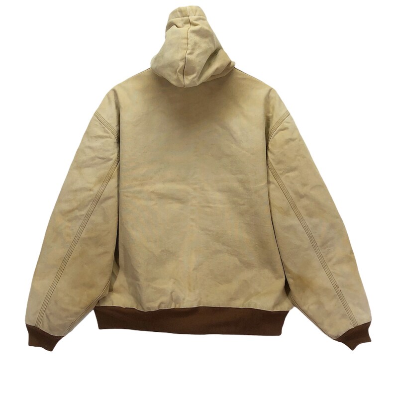 May include: A tan hooded jacket with a brown ribbed waistband. The jacket is made of a thick, durable fabric.