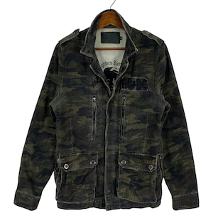 May include: A camouflage print utility jacket featuring a high collar, long sleeves, and multiple pockets with snap closures. The front displays a black AC/DC patch on the chest, while the interior lining shows text reading Fighters Summer.