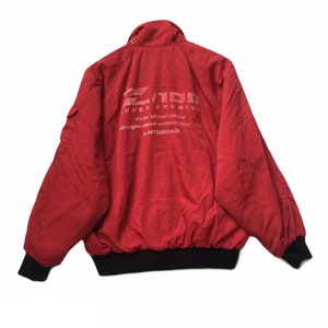 May include: Red bomber jacket with a black zipper and black ribbed cuffs. The back of the jacket has white text that reads "Z/100 SUPER PREMIUM It's the ultimate gasoline with engine-deposit-control additives T/C by MITSUBISHI OIL."