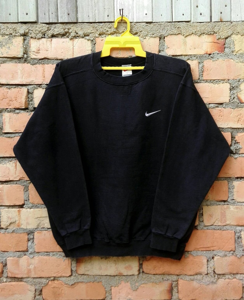May include: Black sweatshirt with a white Nike swoosh logo on the front.
