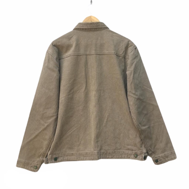 K&ouml;nnte beinhalten: Eine braune Jeansjacke mit Knopfleiste und langen &Auml;rmeln.