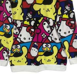 Op de afbeelding: Een wit longsleeve sweatshirt met een kleurrijke all-over print met cartoonfiguren zoals Hello Kitty, My Melody en Keroppi.