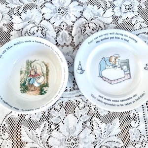 May include: Two white ceramic plates with illustrations and text from a children's story. One plate is a bowl with a rabbit carrying a basket. The other plate shows a rabbit in bed. Text surrounds the edges.