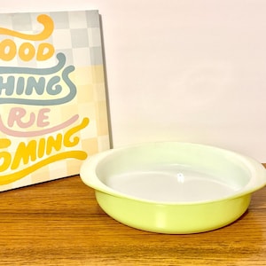 Puede incluir: Un plato poco profundo, redondo y verde claro con interior blanco. El plato está sobre una superficie de madera junto a un letrero con la inscripción "GOOD THINGS ARE COMING" en letras coloridas.