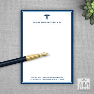 May include: A white notepad with a blue border and the text "HENRY RUTHERFORD, M.D." is displayed. A gold-tipped pen and a small succulent plant are also visible. The notepad has a medical symbol at the top.