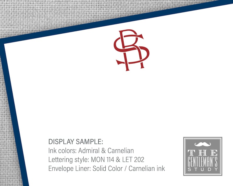 May include: A display sample of a stationery set with a red monogram of the letters "RS" in a decorative font. The text "DISPLAY SAMPLE:" is written in black, followed by the text "Ink colors: Admiral & Carnelian", "Lettering style: MON 114 & LET 202", and "Envelope Liner: Solid Color / Carnelian ink". The text "THE GENTLEMAN'S STUDY" is written in black with a gray background and a gray mustache graphic.