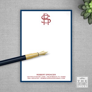 May include: A white notepad with a dark blue border features a burgundy monogram and the name "ROBERT SPENCER" in red. A gold-tipped pen rests on the notepad. The text includes an address, phone number, and email. A succulent plant is in the background.