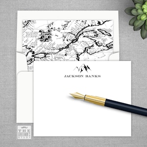 May include: White stationery with a black and white vintage map design on the back. The front features a black mountain range graphic with the text "JACKSON BANKS" underneath.